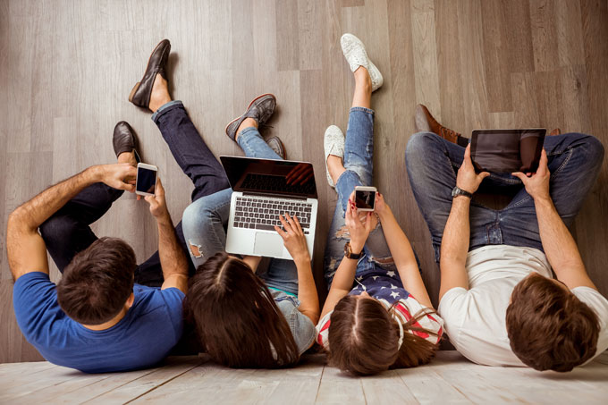 jovens olhando para telas de gadgets e laptops