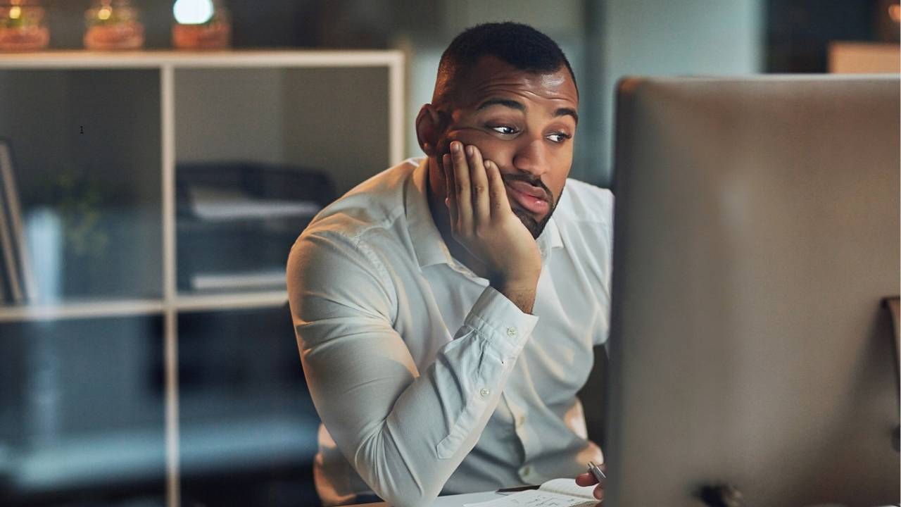 Homem entediado olhando para a tela do computador.