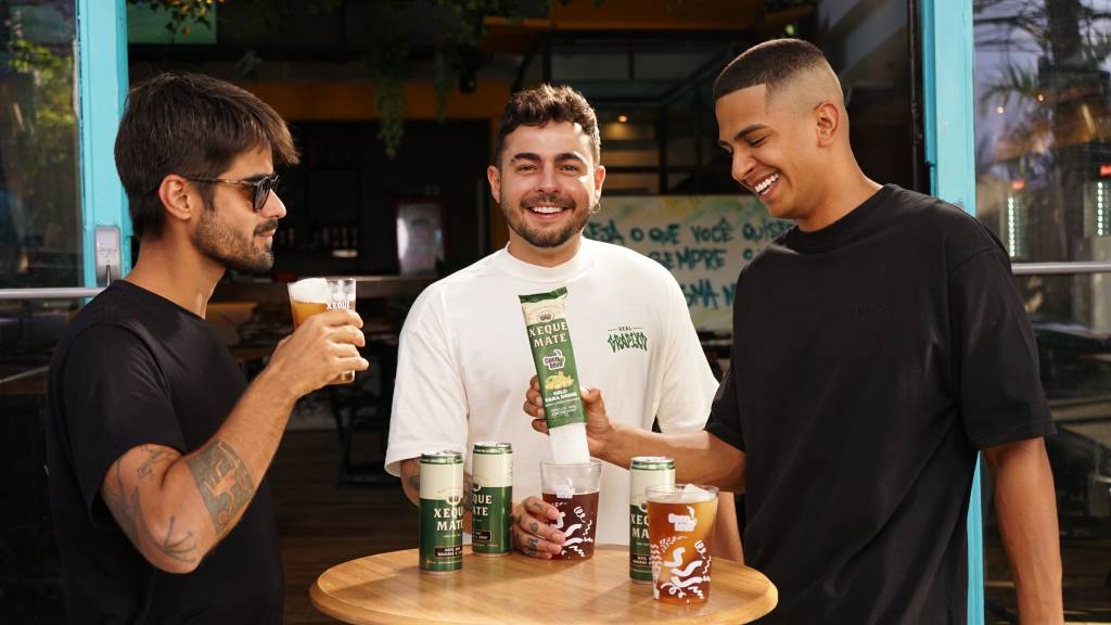 três homens brindando com uma lata verde de bebioda
