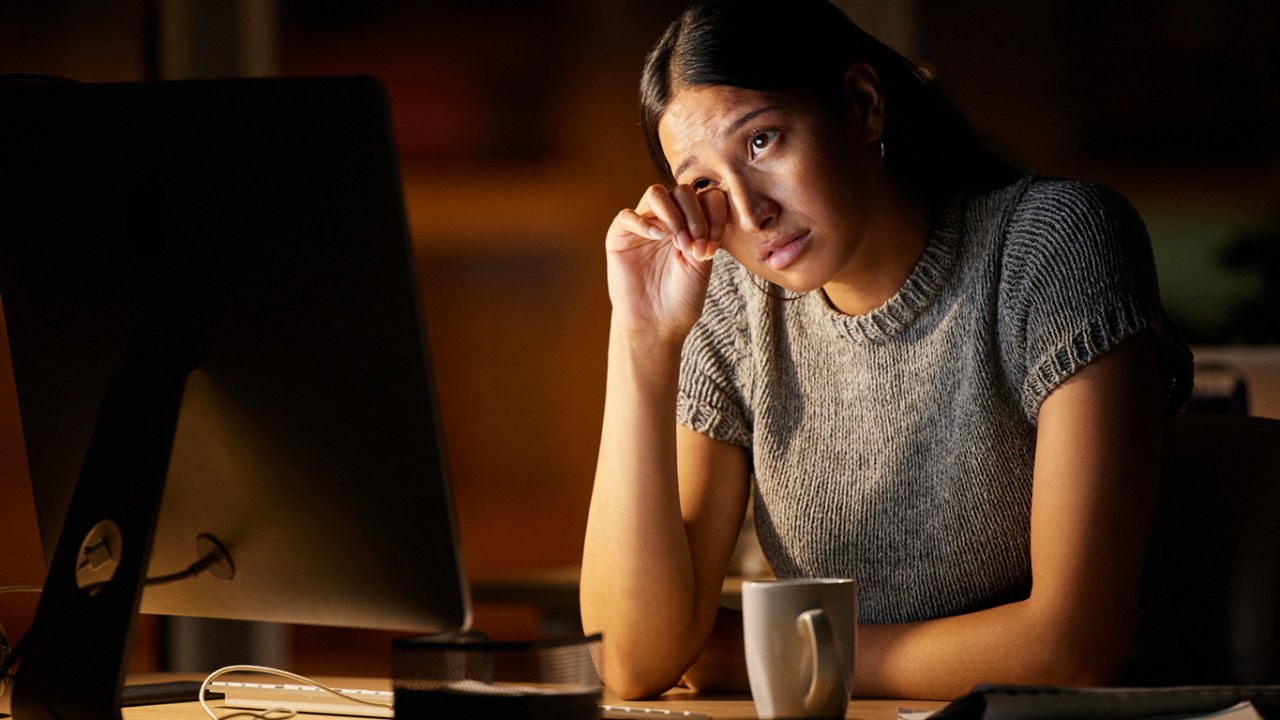 jovem empresária olhando estressado enquanto trabalha em um computador em um escritório à noite.