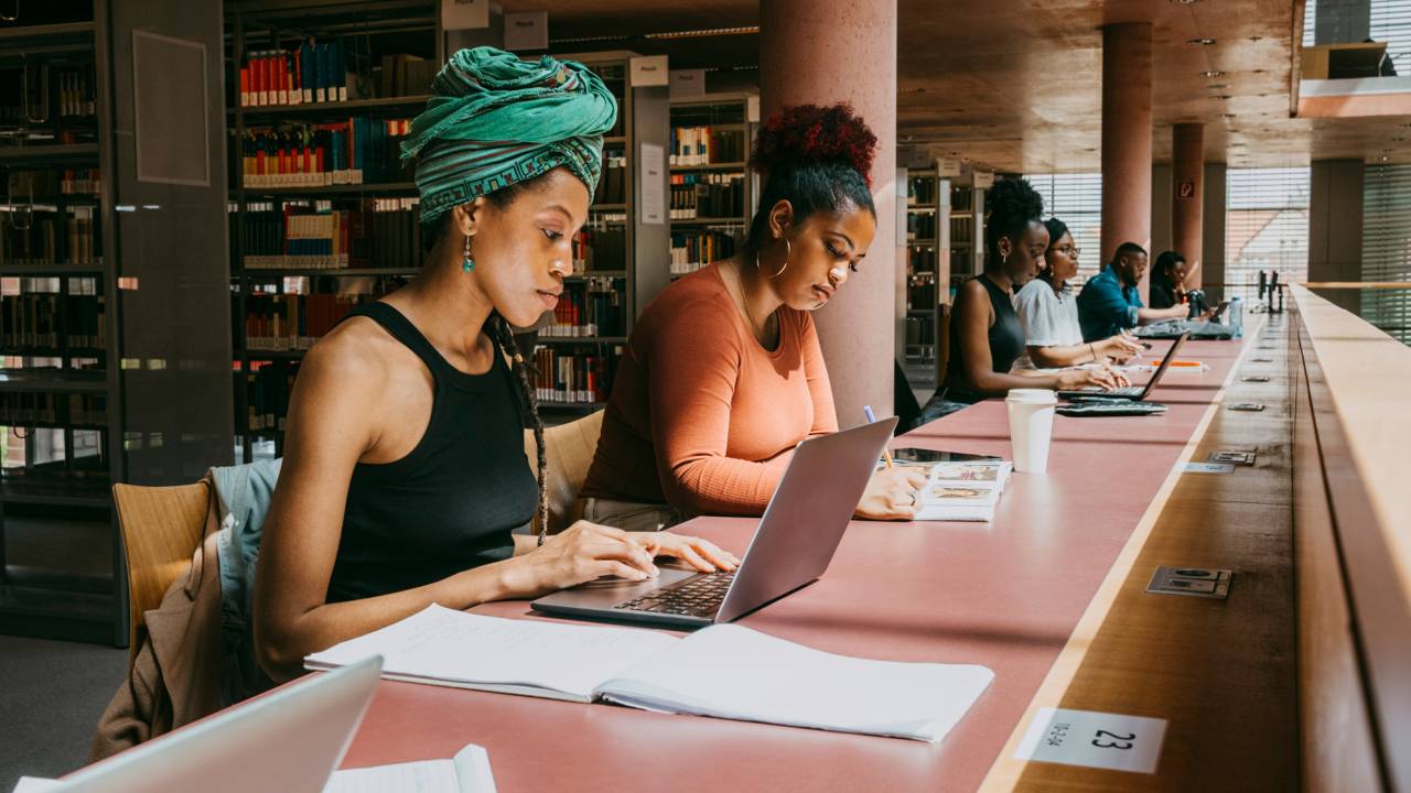 Grupo de pessoas estudando em uma biblioteca.