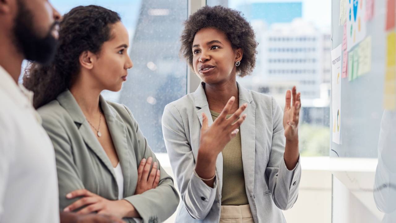 Mulher negra explicando diretrizes para seus colegas de equipe.