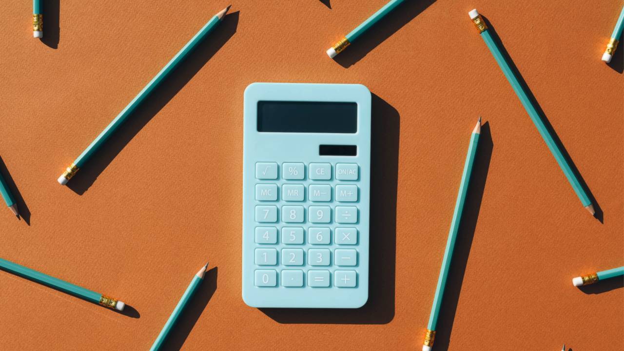 Ilustração 3D de uma calculadora e vários lápis sob fundo marrom.